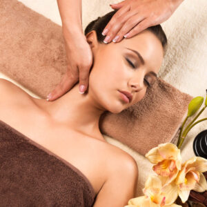 Portrait of beautiful young woman relaxing with head massage at spa salon.